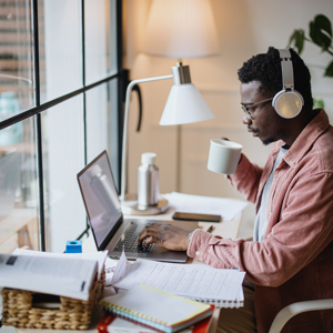 Man sitting at desk studying on laptop surrounded my notes and textbooks