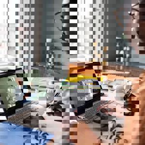 woman watching revision session on laptop and taking notes