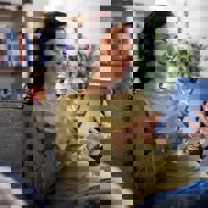 Woman relaxing on sofa with headphones looking at tablet